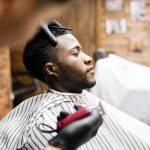 Man wrapped in napkin sitting in armchair in barbershop